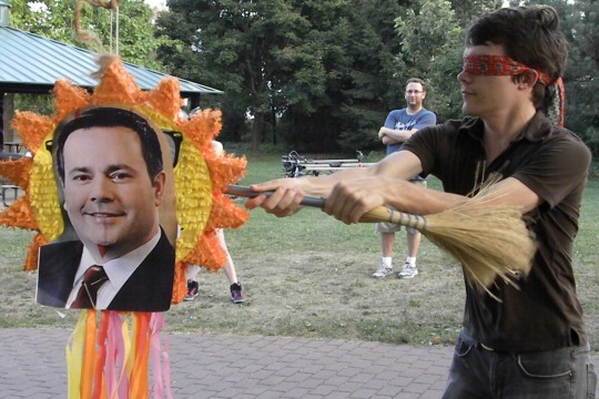 A protester strikes a pinata featuring a picture of Immigration minister Jason Kenney at a rally at Riverside Park on Tuesday. (Greg Beneteau)